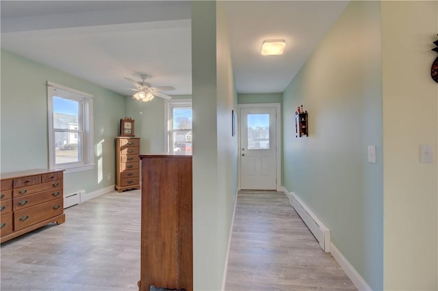 corridor featuring light wood-style floors, plenty of natural light, and a baseboard heating unit