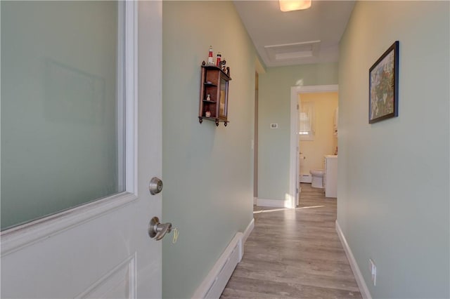 hall featuring attic access, light wood-style flooring, and baseboards