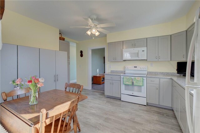 kitchen featuring white appliances, gray cabinets, ceiling fan, light stone counters, and light wood-type flooring