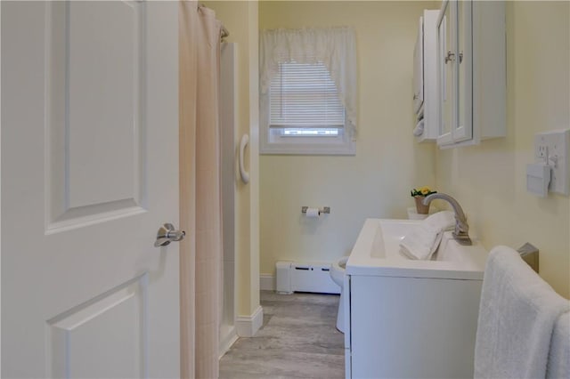 bathroom featuring curtained shower, a baseboard radiator, wood finished floors, vanity, and baseboards