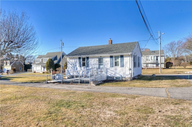 bungalow with roof with shingles, a chimney, and a front lawn