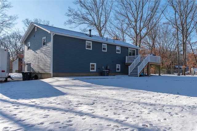 snow covered back of property with a deck