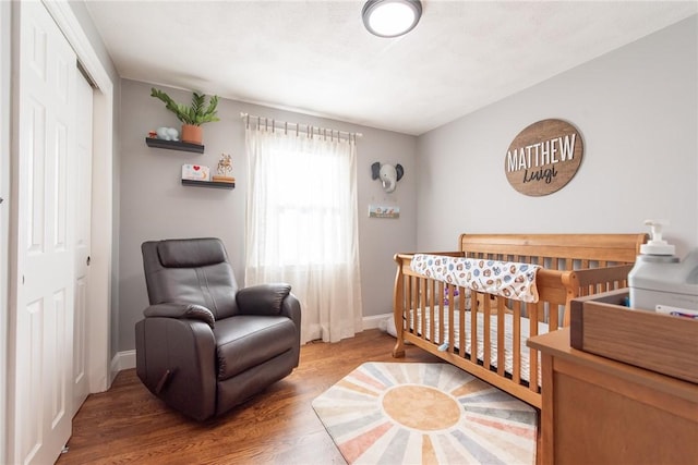 bedroom with a crib, hardwood / wood-style floors, and a closet