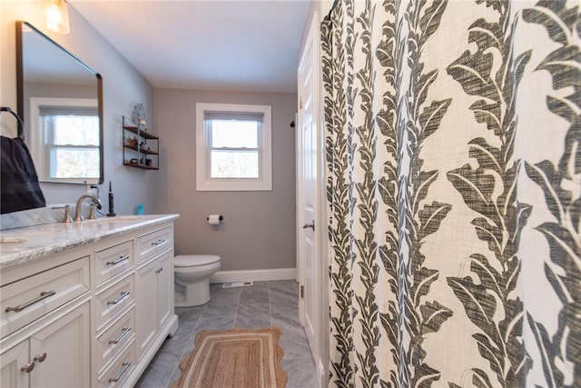 bathroom with vanity, toilet, and a healthy amount of sunlight