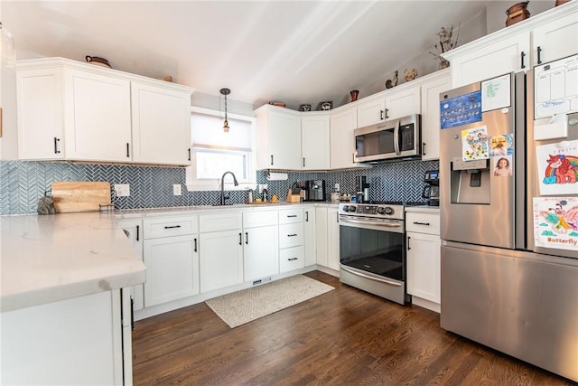 kitchen with dark wood-type flooring, sink, pendant lighting, stainless steel appliances, and white cabinets