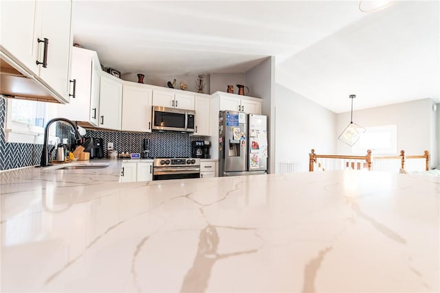 kitchen featuring pendant lighting, white cabinetry, sink, stainless steel appliances, and light stone countertops