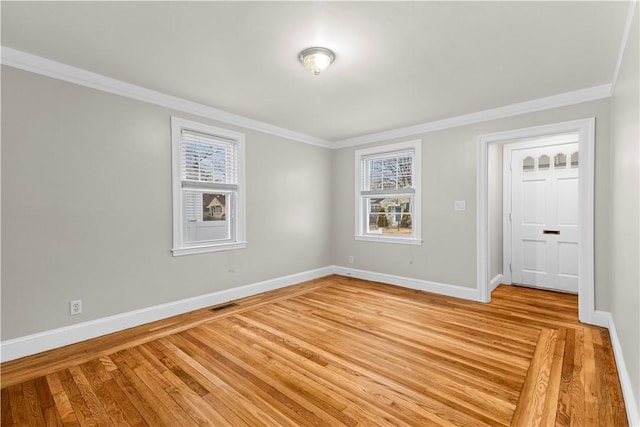 empty room with ornamental molding and light hardwood / wood-style floors