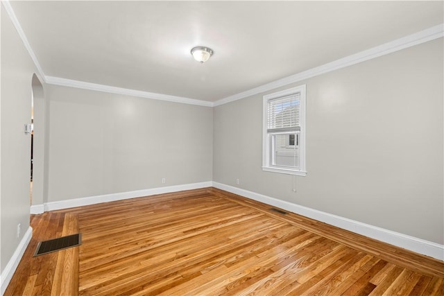 empty room featuring hardwood / wood-style flooring and crown molding