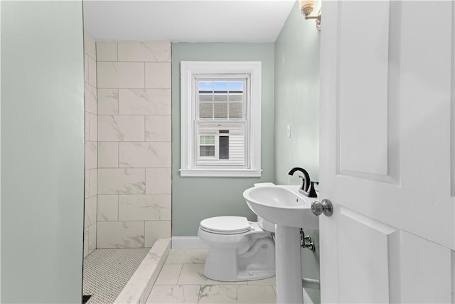 bathroom featuring a tile shower and toilet