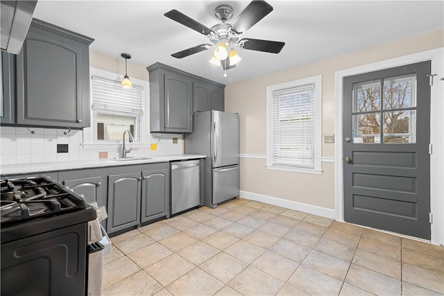 kitchen featuring appliances with stainless steel finishes, gray cabinets, sink, and backsplash