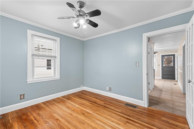 spare room featuring crown molding, a healthy amount of sunlight, and light wood-type flooring