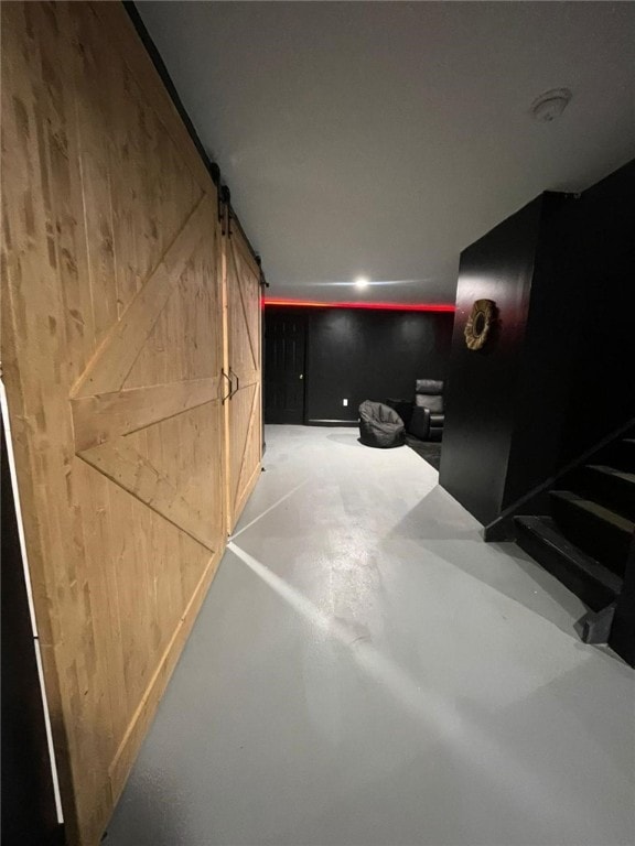 cinema room featuring a barn door, concrete floors, and wood walls