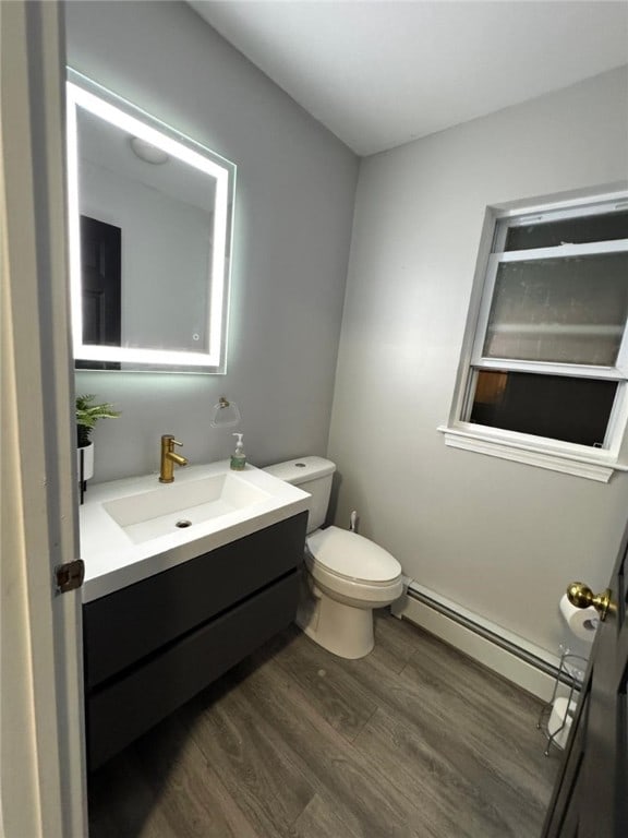 bathroom featuring hardwood / wood-style flooring, a baseboard radiator, vanity, and toilet