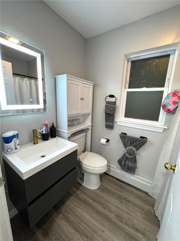 bathroom with vanity, a baseboard heating unit, wood-type flooring, and toilet