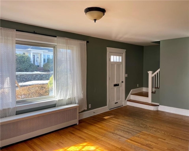 foyer with wood-type flooring and radiator heating unit