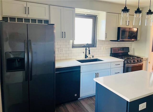 kitchen featuring pendant lighting, sink, appliances with stainless steel finishes, white cabinetry, and dark hardwood / wood-style flooring