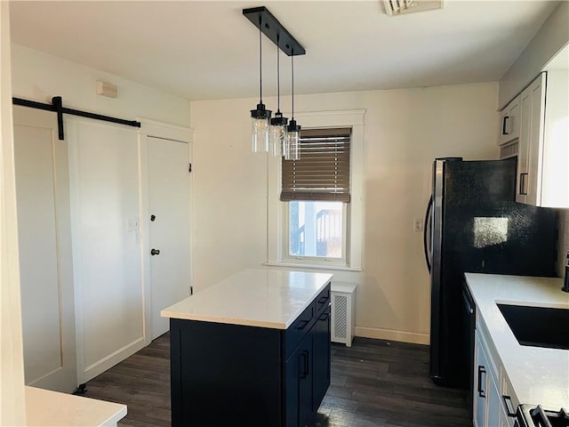 kitchen with pendant lighting, dark wood-type flooring, a center island, white cabinets, and a barn door