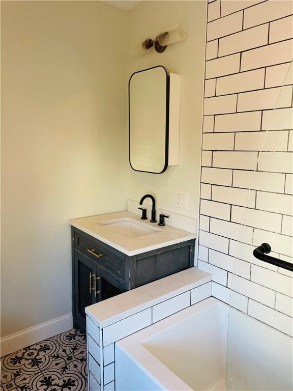 bathroom with tiled shower / bath combo, vanity, and tile patterned floors