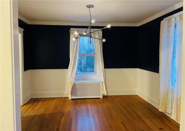 unfurnished dining area with ornamental molding, radiator, a notable chandelier, and dark hardwood / wood-style flooring