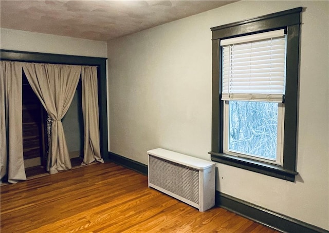 spare room with radiator heating unit and hardwood / wood-style floors