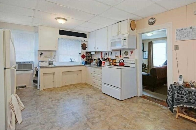 kitchen with a paneled ceiling, white cabinets, and white appliances