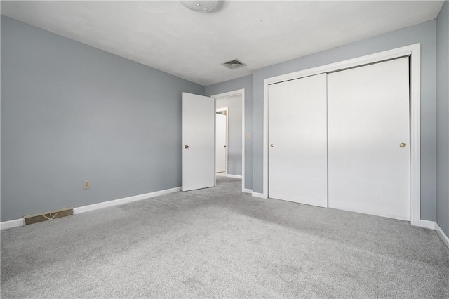 unfurnished bedroom with light colored carpet and a closet