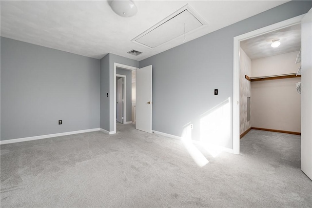 unfurnished bedroom featuring a spacious closet, light carpet, and a closet