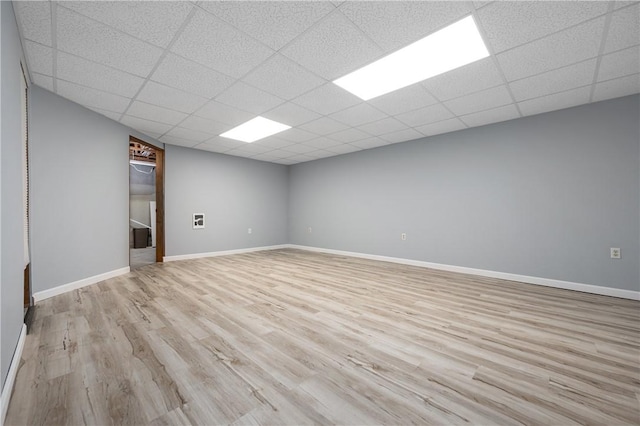 empty room with a paneled ceiling and light hardwood / wood-style floors