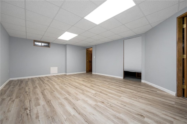 basement featuring a paneled ceiling and light wood-type flooring