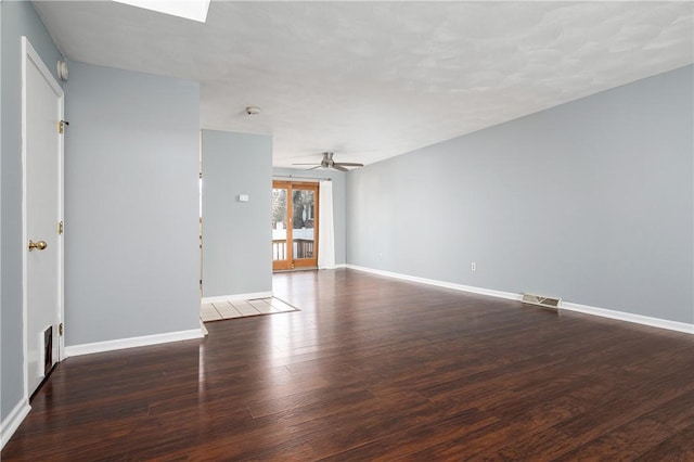 empty room featuring a skylight, dark hardwood / wood-style floors, and ceiling fan