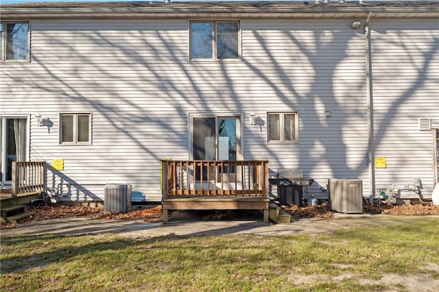 rear view of house featuring a deck, central AC unit, and a lawn