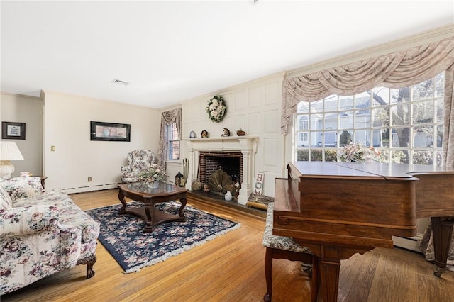 living room featuring a brick fireplace, hardwood / wood-style flooring, a wealth of natural light, and a baseboard radiator