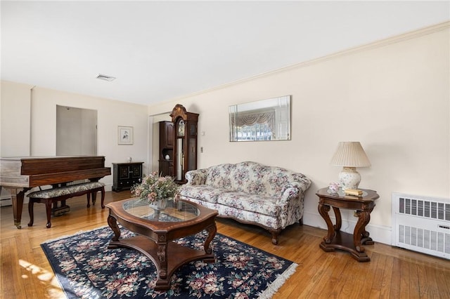 living room with radiator, hardwood / wood-style flooring, and ornamental molding