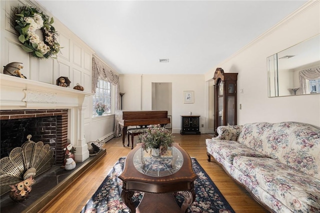 living room with crown molding, wood-type flooring, and a baseboard radiator