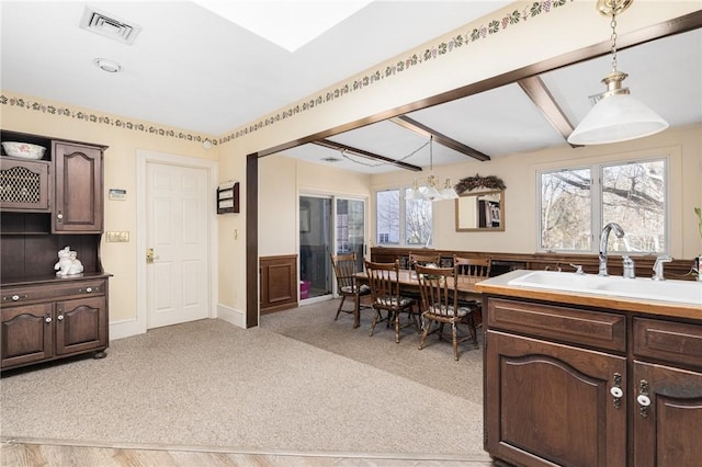 kitchen featuring light carpet, decorative light fixtures, sink, and dark brown cabinets