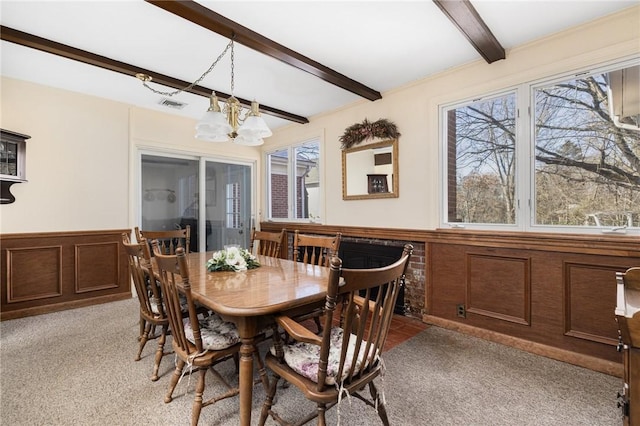 dining space with an inviting chandelier, beam ceiling, and light colored carpet