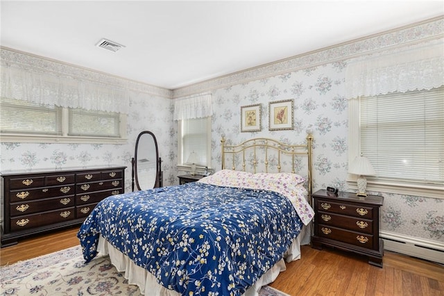 bedroom with light hardwood / wood-style floors and baseboard heating