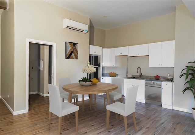 kitchen with a wall mounted air conditioner, hardwood / wood-style flooring, white cabinets, and dishwasher