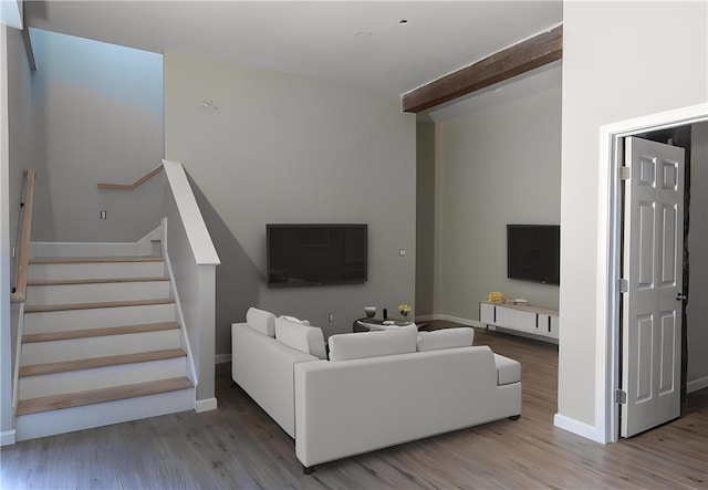 living room featuring beamed ceiling and light hardwood / wood-style floors