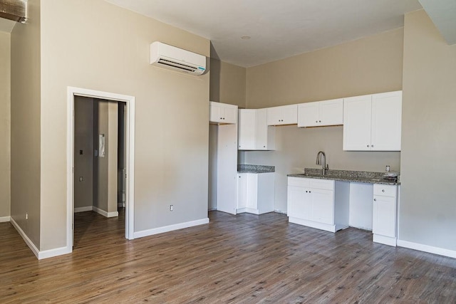 kitchen with white cabinetry, a wall mounted air conditioner, sink, and hardwood / wood-style flooring