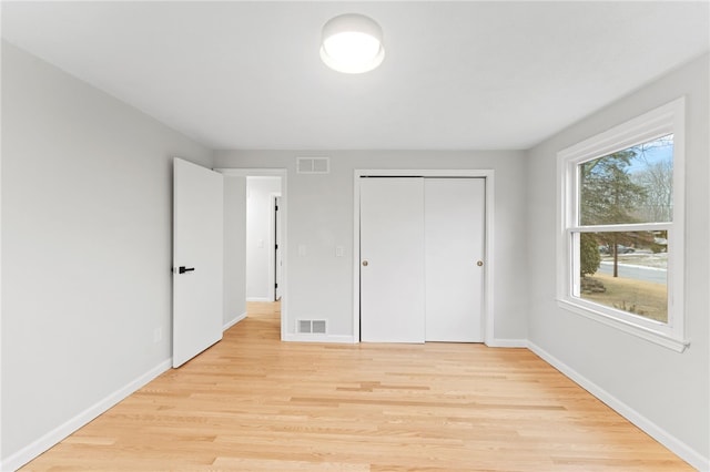 unfurnished bedroom with light wood-type flooring and a closet