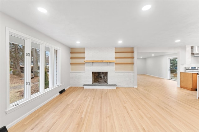 unfurnished living room with a brick fireplace and light hardwood / wood-style flooring