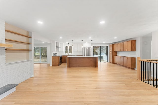 kitchen with stainless steel appliances, decorative light fixtures, a kitchen island, and light wood-type flooring