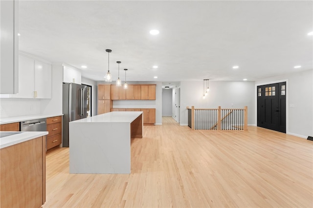 kitchen with light wood-type flooring, a kitchen island, pendant lighting, stainless steel appliances, and white cabinets