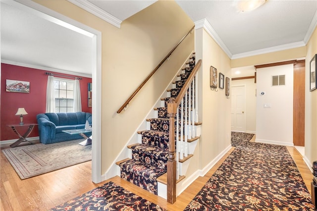 stairs featuring wood-type flooring and ornamental molding