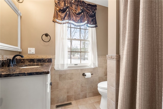 bathroom with vanity, tile walls, tile patterned floors, and toilet