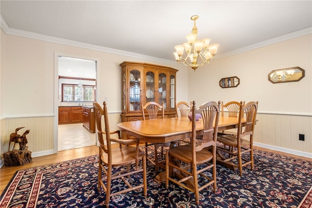 dining room featuring a notable chandelier, light hardwood / wood-style flooring, ornamental molding, and sink