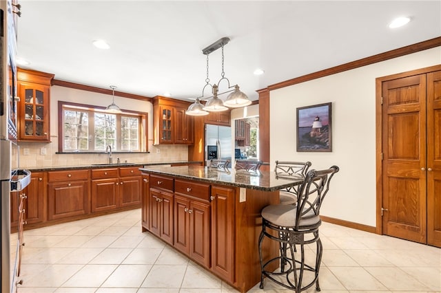 kitchen with a kitchen island, stainless steel built in refrigerator, sink, a breakfast bar area, and dark stone counters