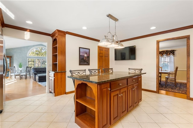 kitchen featuring dark stone countertops, hanging light fixtures, light tile patterned floors, and a kitchen island