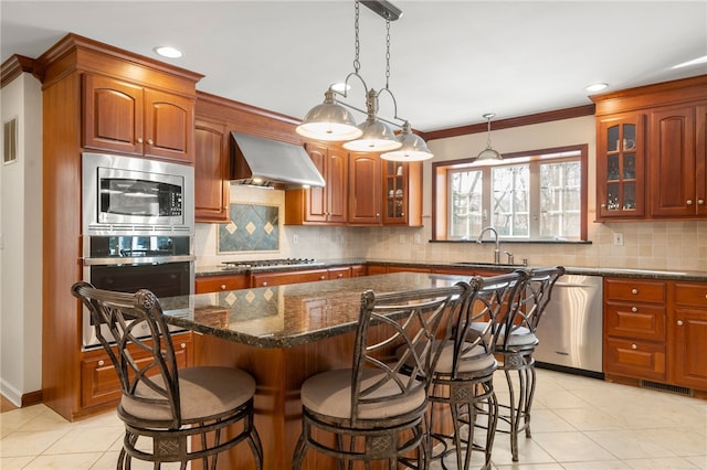 kitchen featuring a center island, wall chimney exhaust hood, and appliances with stainless steel finishes